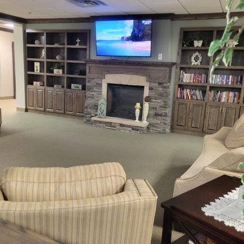 Comfortable lounge with seating, fireplace, and bookshelves fostering a warm community atmosphere.