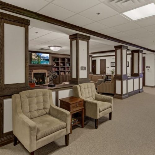 Spacious lounge with comfortable seating, warm fireplace, and inviting atmosphere for residents.