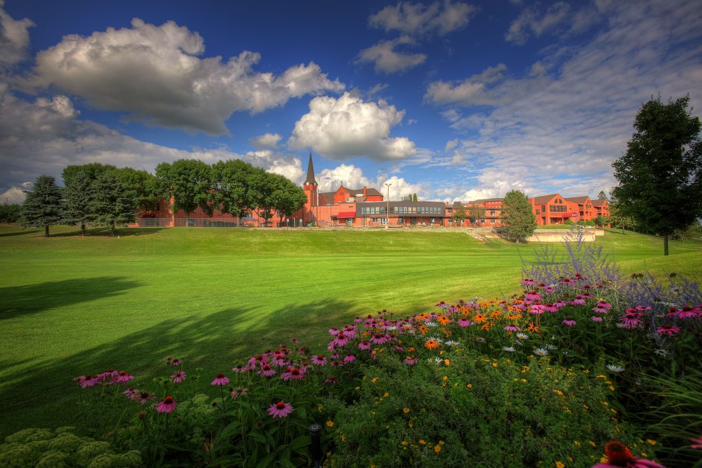Well-maintained gardens and open green spaces surrounding a welcoming retirement community building.