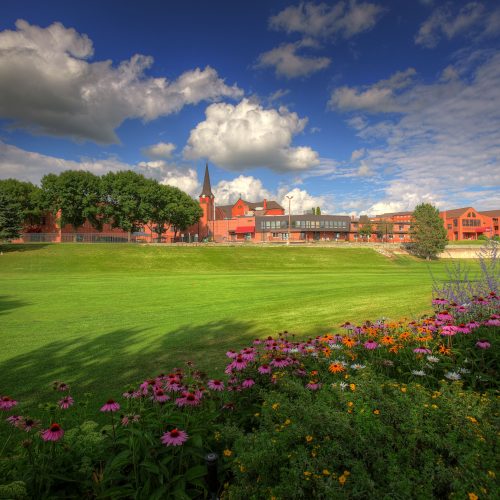 Well-maintained gardens and open green spaces surrounding a welcoming retirement community building.