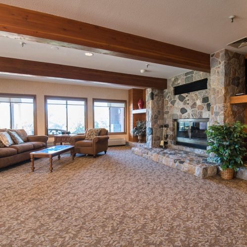 Warm, inviting lounge with plush seating, stone fireplace, and natural light for community gatherings.