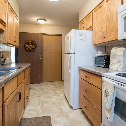 Well-equipped kitchen with warm wood cabinets and welcoming autumn decor near the entrance.
