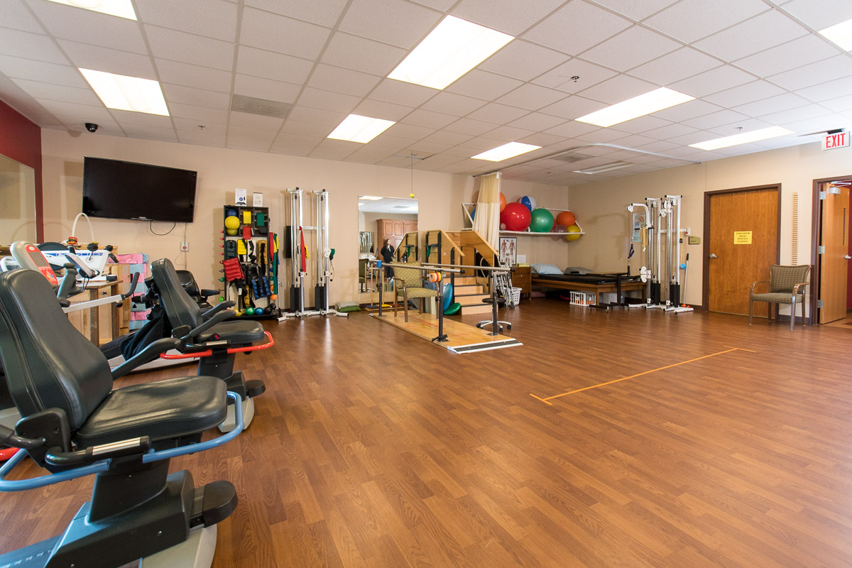 Bright and spacious fitness room with exercise equipment and therapy tools promoting active community living