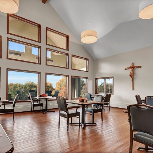 Dining room with large windows, warm wood floors, and comfortable seating for social meals.