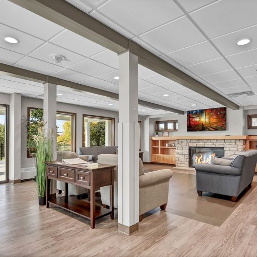 Inviting lounge with comfortable seating, a warm fireplace, and large windows overlooking greenery.