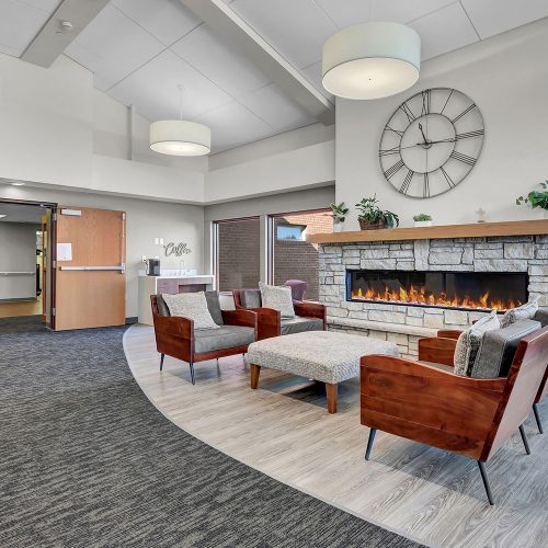 Welcoming lobby with seating around a fireplace, natural light, and a peaceful atmosphere.