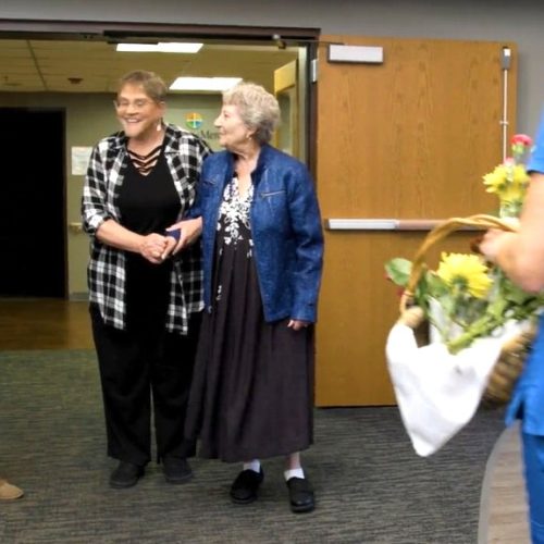 Residents and staff warmly greet each other in a welcoming and friendly lobby setting.