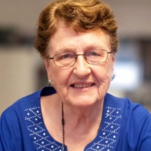 Smiling elderly woman in a bright room, exuding warmth and a welcoming spirit.