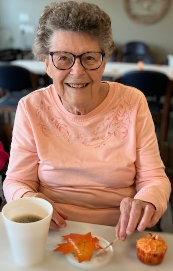 Woman sitting at table with coffee and cupcake.