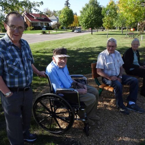 Seniors enjoying a sunny afternoon together outdoors in a peaceful neighborhood setting.