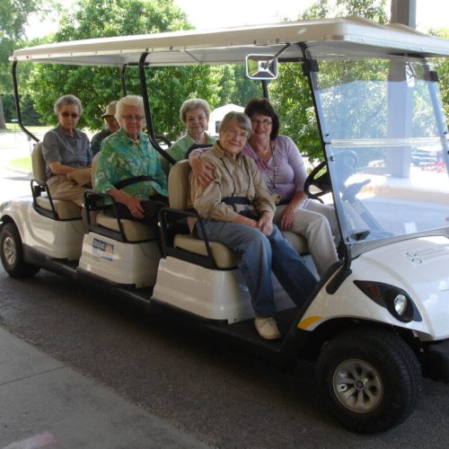Residents enjoy a group ride outdoors, sharing smiles and companionship in a peaceful setting.