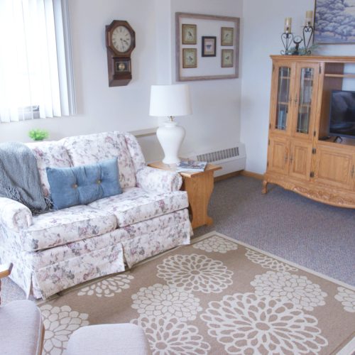 Bright living room with floral seating, soft lighting, and a welcoming atmosphere for community gatherings.