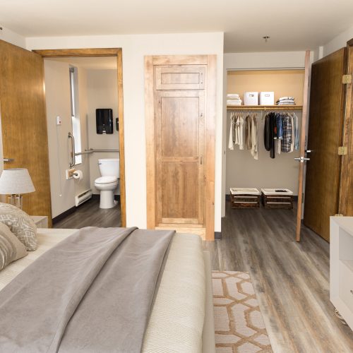 Bright and inviting bedroom with accessible bathroom, walk-in closet, and warm wood accents.