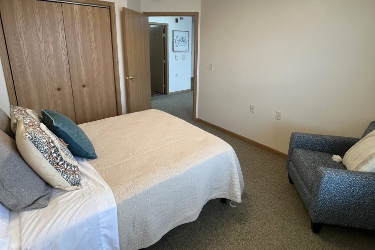 Sunlit bedroom with comfortable bed, inviting armchair, and a welcoming, peaceful atmosphere.
