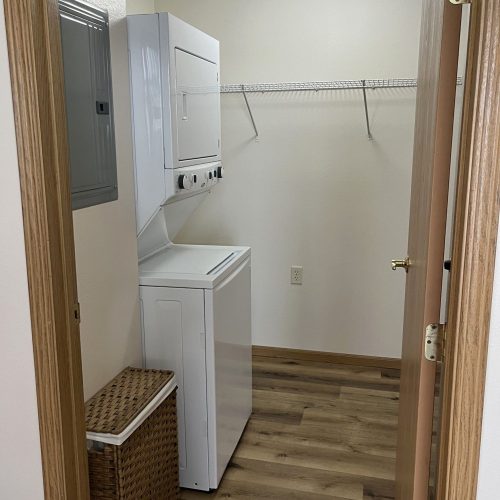 Bright, clean laundry room with washer, dryer, and laundry basket in a welcoming community space.