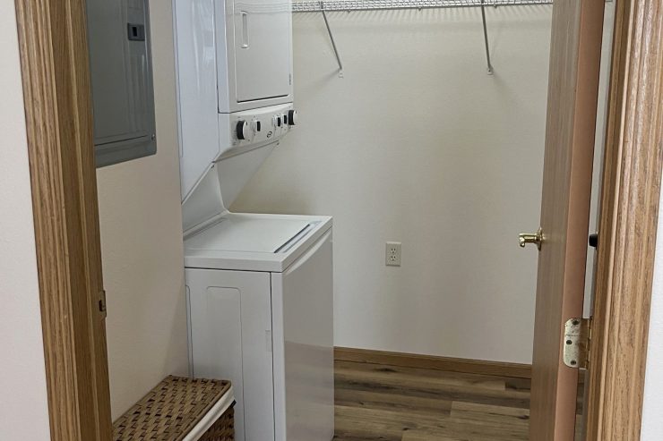 Bright, clean laundry room with washer, dryer, and laundry basket in a welcoming community space.