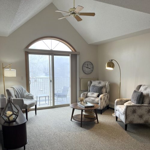 Bright common room with comfortable seating, soft lighting, and a view to a quiet balcony.