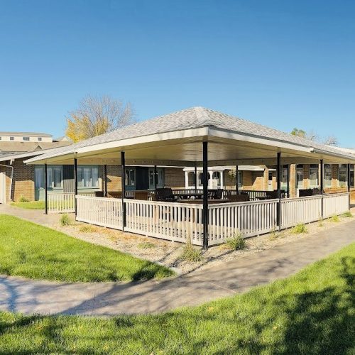 Spacious outdoor patio with shaded seating surrounded by green lawns, perfect for socializing.