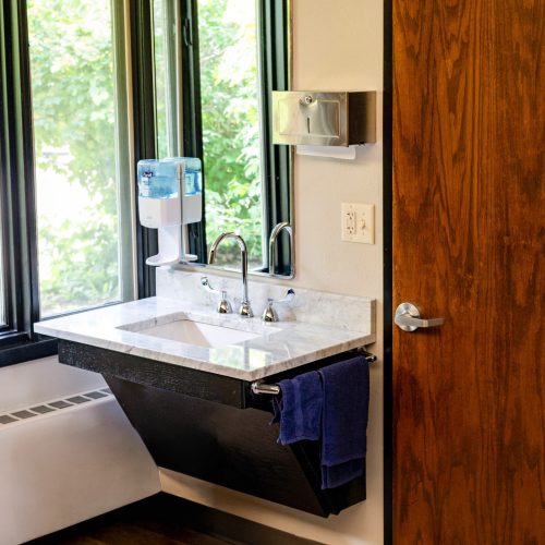 Bright room with a sleek marble sink, hand soap dispenser, and natural light from a window.