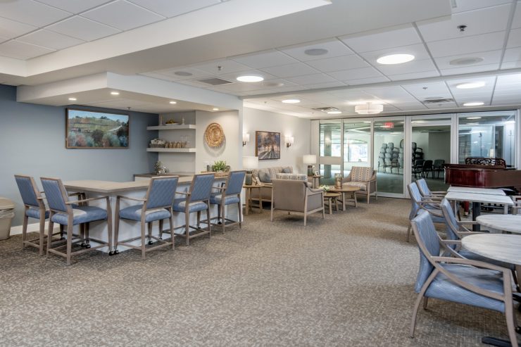 Spacious community room with seating, soft lighting, and a grand piano for social gatherings.