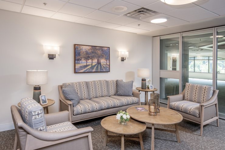 Inviting sitting area with comfortable patterned furniture, warm lighting, and scenic artwork.