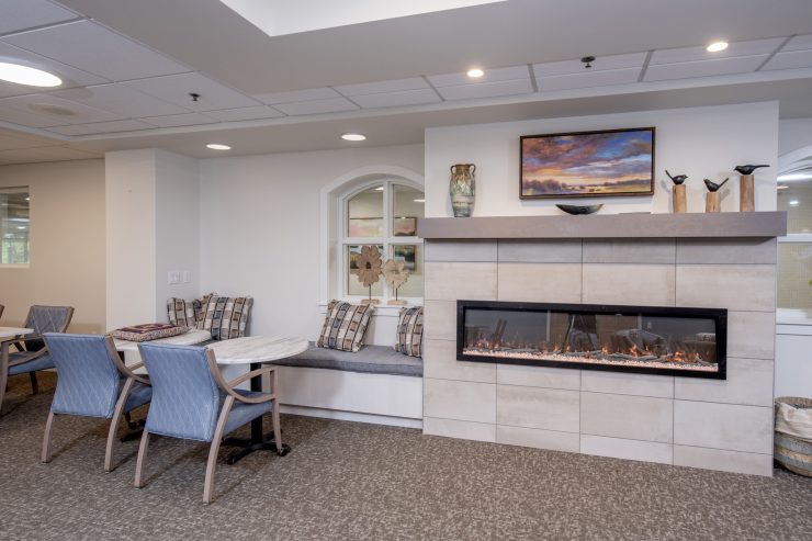 Warm seating area with fireplace, soft cushions, and tasteful decor fostering relaxation and community.