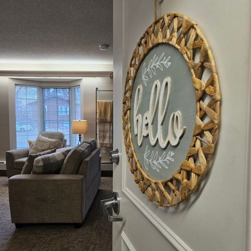 Welcoming doorway opens to a bright living room with plush seating and warm lighting.