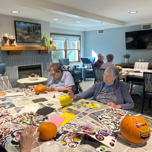 Seniors engaging in creative pumpkin painting in a bright, welcoming community room.