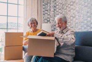 Senior couple sharing smiles while unpacking cherished memories in a bright living space.