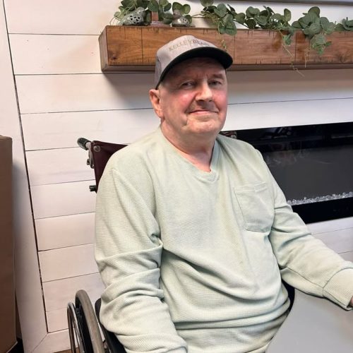 Resident enjoying a peaceful moment in a bright, welcoming common area with homelike decor.
