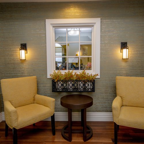 Two comfortable yellow armchairs with a small table between, softly lit for a welcoming feel.