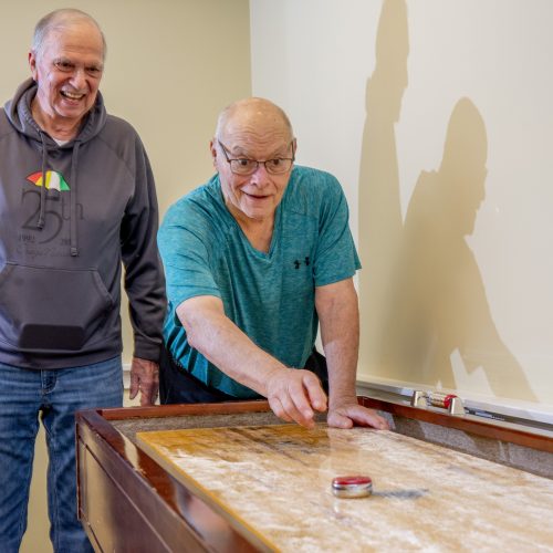 Two senior men enjoy a friendly game together in a bright, welcoming room.