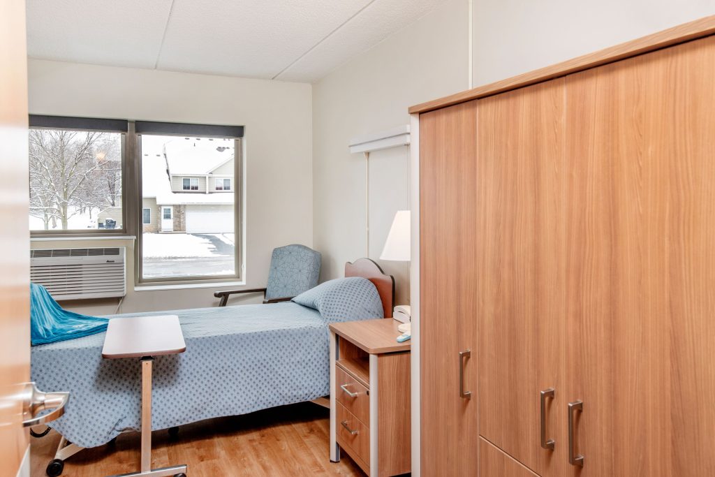 Private, comfortable room with natural light, warm wood furnishings, and a peaceful view.