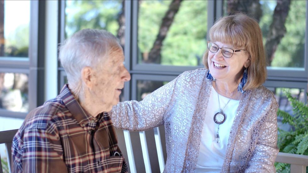 Image of elderly man sitting with a woman smiling.