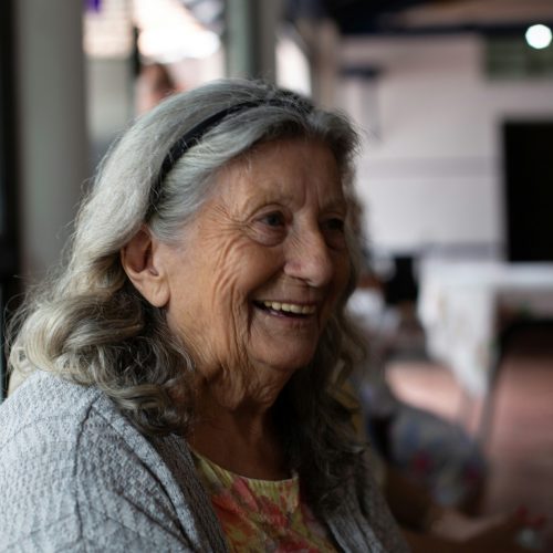 Smiling elderly woman enjoying a bright, welcoming community space with natural light.
