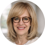 Smiling woman with glasses radiating warmth and friendliness in a bright, welcoming space.