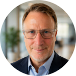 Friendly gentleman with glasses smiling warmly in a bright, welcoming living space.