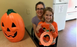 Mother with daughter on her lap next to a pumpkin craft.