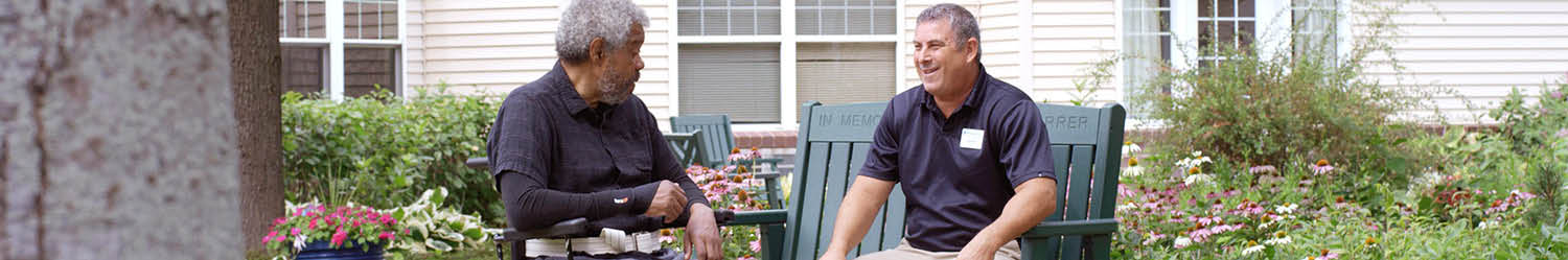 Two men sitting together outside talking 